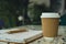 Hot latte coffee in craft recycling paper cup with paper notebook. Coffee break. Online job or studying co-working space