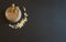 A hot maca latte in a glass, with maca powder sprinkled next to it, on a black background with copy space