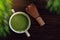 Hot Matcha Green Tea Latte Cup on Wooden Table with Chasen or Bamboo Whisk. Japanese Traditional Drink. Blurred Green Leaf as