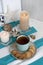A hot mug of black tea with cookies on a striped tablecloth, wax candles, decorative starfish, seashell, pile of
