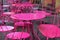 Hot pink metal tables and chairs out on brick sidewalk