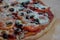 Hot pizza from a wood-fired oven with cheese, tomatoes, olives and finely chopped salami