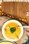 hot pumpkin soup in glass pan and in white plate, decorated with mini carrot, pumpkin seeds, mushroom, honey agaric and green kelp