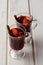 Hot red mulled wine or gluhwein in glass with orange, cinnamon sticks and anise on white wooden background