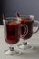 Hot red mulled wine or gluhwein in glass with orange, cinnamon sticks and anise on white wooden background