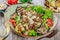 Hot salad with veal, mushrooms, salad leaves, eggplant, zucchini, tomatoes, garnished with grated almonds and Parmesan cheese and