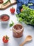 Hot sauce adjika. Homemade appetizer with pepper and tomatoes in a jar on light background with fresh herb and vegetables