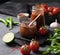 Hot sauce adjika. Homemade appetizer with peppers and tomatoes in a jar on a dark background with vegetables and herbs. Rustic