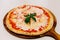 Hot served Pizza Margherita on wooden plate with olive oil