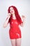 Hot sexual redheaded girl with plus size body wears fashion latex rubber red dress and posing on white studio background alone. ch