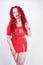 Hot sexual redheaded girl with plus size body wears fashion latex rubber red dress and posing on white studio background alone. ch