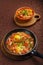 hot shakshuka in a frying pan sprinkled with green onions and chelnt on the sabbath table.