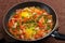 hot shakshuka in a frying pan sprinkled with green onions on a wooden board.