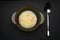 Hot soup with steam in the soup, a spoon in a silver and aluminum black glassware on a dark background