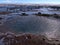 Hot spring of thermal water in Geysir in geothermal area Haukadalur, part of Golden Circle, Iceland in winter with reflections.