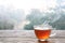 Hot steaming tea in a glass cup on a rustic wooden outdoor table on a cold foggy winter day, copy space, selected focus, narrow