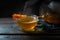 Hot steaming tea a glass cup with a stick of rock candy on a dark rustic wooden table, copy space, selected focus