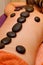 Hot stones lined on young woman\'s back for massage