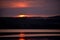 Hot sunset above the forest. Refelctions of red clouds in the water of the lake. bright colors at the end of a summer day