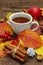 Hot tea with colorful autumn leaves, acorns, cinnamon and rosehip berries