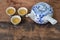 Hot tea pot with three ceramic cups on wooden table