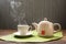 Hot tea with steam and teapot on a table background