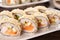 Hot tempura sushi rolls with cream cheese on white dish on black background. Japanese traditional fusion food style