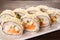 Hot tempura sushi rolls with cream cheese on white dish on black background. Sushi menu. Japanese food. Futomaki