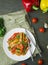 Hot vegetable salad with chicken, zucchini and pepper, sprinkled with sesame seeds and herbs on a wooden table. Asian food. View