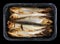 Hot  whole  smoked  sprat  Baltic sea  fish with heads and guts in plastic box  isolated