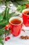 Hot winter or Christmas tea in ceramic red cups. Fir tree branches, lemon slice, spices and berries