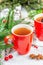 Hot winter or Christmas tea in ceramic red cups. Fir tree branches, lemon slice, spices and berries