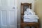 Hotel bathroom decor closeup. White towels,  on wooden stool and a door. Natural colors, still life. Studio shot