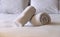 Hotel bedroom. White fluffy, rolled towels, linen sheets and pillows on a bed. Close up view