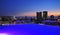 hotel pool, at sunset city and buildings with modern apartments and offices at night illumination in background-marriott