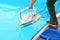 Hotel staff worker cleaning the pool. A pool cleaner holds a robot cleaner