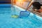 Hotel staff worker cleaning the pool. A pool cleaner holds a robot cleaner