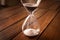 Hourglass containing white sand on a rustic wooden board