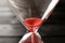 Hourglass with flowing sand on table, closeup