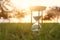 Hourglass in the grass time during sunset. vintage style.