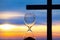 Hourglass has finished counting time on the background of the sunset and a wooden cross. End of life. The value of time in life