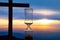 Hourglass has finished counting time on the background of the sunset and a wooden cross. End of life. The value of time in life