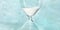 Hourglass panorama. Time is running out concept. A close-up of a sand clock on a teal blue background