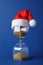 Hourglass and Santa hat on blue. Christmas countdown