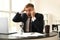 Hourglass on table of stressed businessman in office