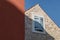 The house on the blue sky background. Roof and window with shutters. Architectural composition.