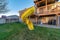 House with bright yellow slide on the deck going down to the grassy yard
