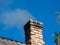 House chimney with white and grey smoke from burning firewood, pellets or briquettes