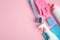 House cleaning tools and cleaning products on pink background. Top view blue sponge, gloves, brush and cleaner bottles. Cleaning