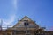 House construction - The roof ridge of the new building stretches behind the scaffolding into the blue sky